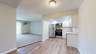Located at 1599 W Irving Park Rd in Itasca, Illinois, this single-floor residence offers a practical and well-appointed layout designed for comfortable everyday living. The open-concept living and dining area is finished with plush carpeting and features a wall-mounted air conditioning unit, baseboard heating, and a large sliding glass door that fills the space with natural light and provides views of the outdoors. A textured ceiling runs throughout the unit, lending a consistent aesthetic from room to room. The kitchen is thoughtfully designed with crisp white shaker-style cabinetry, marble-look countertops, recessed lighting, and a full suite of stainless steel appliances, including a refrigerator, electric range, over-the-range microwave, and dishwasher. Light wood-style flooring grounds the kitchen and entry areas, creating a clean contrast with the carpeted living and bedroom spaces. The bedroom is generously sized with a window that allows natural light in, soft carpeting underfoot, and a dedicated closet with built-in shelving for ample storage. The full bathroom includes a tiled tub-shower combination, toilet, and vanity with mirror. An entry foyer with hardwood-style flooring and an electrical panel completes this functional and move-in-ready home.
