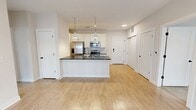 This contemporary 840 square foot apartment offers a harmonious blend of style and functionality. The space features two bedrooms, including a primary bedroom of 140 square feet, and three well-appointed bathrooms. The open-concept design seamlessly integrates the kitchen and living area, creating a spacious and inviting atmosphere.

The kitchen is a standout feature, boasting sleek white cabinetry, stainless steel appliances, and a contrasting dark countertop. Pendant lighting adds a touch of modern elegance. The living area is bathed in natural light, thanks to large windows with horizontal blinds. Wood-look flooring throughout enhances the modern aesthetic and provides durability.

Both bedrooms offer ample space and are carpeted for comfort. The bathrooms are designed with practicality in mind, featuring granite countertops and clean, white fixtures. Generous closet space, including walk-in options, provides abundant storage solutions.

Recessed lighting throughout ensures even illumination, while the neutral color palette creates a bright, airy feel. This single-floor layout maximizes space efficiency, making it an ideal urban dwelling for those seeking a contemporary lifestyle in a well-designed, compact space.