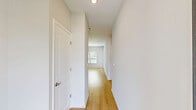 This single-story home offers a practical and comfortable layout across two bedrooms, two bathrooms, a combined kitchen and living area, a dedicated laundry room, two closets, and an attached garage. The exterior features a stucco finish with a tiled roof, manicured front landscaping, and a concrete driveway leading to the garage.

The kitchen is well-equipped with white shaker-style cabinetry, granite-look countertops, stainless steel appliances including a refrigerator, range, microwave, and dishwasher, all set atop light hardwood-style flooring that extends throughout the main living areas.

The bathrooms are clean and functional, featuring hardwood-style flooring, a tub-shower combination with built-in shelving, and granite-accented vanities. The dedicated laundry room accommodates a full-size top-loading washer and dryer, complete with overhead wire shelving for storage.

The bedrooms feature plush carpet flooring, and the primary bedroom includes a walk-in closet outfitted with wire shelving systems. A glass-panel rear door in the living area opens to a generous backyard with an open lawn and a backdrop of mature trees, providing a private, natural setting. The home also benefits from a modern HVAC system installed on the exterior.