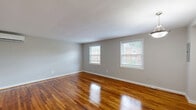 Located at 2810 Ninth St S in Arlington, VA, this 2-bedroom, 1-bathroom residence offers a functional and well-designed single-floor layout. Rich, polished hardwood floors run throughout the living spaces and bedrooms, lending warmth and a classic character to the interior. The neutral gray walls provide a clean, versatile backdrop throughout.

The living room is generously proportioned and benefits from a wall-mounted mini-split HVAC unit for efficient climate control. Two large windows allow natural light to fill the space, with views of the surrounding neighborhood. The primary bedroom is spacious, offering ample room for furnishings, while the second bedroom also features a large window for natural light.

The kitchen is outfitted with rich dark-wood cabinetry, granite-style countertops, a black electric range, and a stainless steel sink — all complemented by light tile flooring and a window that brightens the space. The bathroom features white subway tile wainscoting, light tile flooring, a dark-wood vanity with a white basin sink, and a window for natural ventilation. A hallway connects the rooms, contributing to the home's efficient and straightforward flow throughout.
