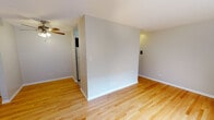 Located at 508 W Melrose St in Chicago's sought-after Lakeview neighborhood, this single-floor unit offers a practical and well-maintained living space with a clean, neutral aesthetic throughout. Warm hardwood flooring extends across the main living areas, reflecting natural light and contributing to a bright, welcoming atmosphere.

The living area is open and versatile, featuring light gray walls, white baseboards, and a ceiling fan overhead. A partial wall divider creates a subtle sense of separation within the open layout. Windows fitted with blinds allow generous natural light to fill the rooms while providing privacy.

The kitchen is thoughtfully updated, showcasing rich dark cabinetry with sleek hardware, stone-look countertops, a stainless steel sink, and a classic white subway tile backsplash. Under-cabinet lighting adds both functionality and ambiance to the cooking space.

The bathroom is clean and efficiently designed, featuring white square wall tiles surrounding a full bathtub with a handheld showerhead, mosaic tile flooring, a dark wood vanity with a white sink, and a large mirrored medicine cabinet above.

Each room benefits from wall-mounted air conditioning units and baseboard heating, ensuring year-round comfort. The overall design is simple, neutral, and move-in ready, making this a practical urban retreat in one of Chicago's most vibrant communities.