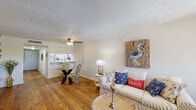 Located at 500 Sabal Palm Cir in Altamonte Springs, Florida, this single-floor residence offers a welcoming coastal aesthetic carried throughout its open, functional layout. The living area serves as the heart of the home, featuring warm hardwood flooring that extends across the main living spaces. A textured ceiling with a ceiling fan adds to the relaxed, casual character of the room, while a large window allows natural light to fill the space and offers a view of the surrounding greenery. The living room comfortably accommodates multiple seating areas, anchored by beach-inspired décor including coastal artwork and nautical accents that reinforce the home's breezy theme. Adjacent to the living area, a dining space with a glass-top table connects seamlessly to a pass-through kitchen, promoting an open and social flow between rooms. The kitchen features a countertop bar area with a view into the main living space. The bathroom is clean and well-appointed, with a white vanity, quartz-style countertop, brushed nickel fixtures, and dual wall mirrors that enhance the sense of space. The overall ambiance of this residence is light, airy, and cohesive, with a consistent coastal design language that makes it feel like a relaxed retreat in the heart of Altamonte Springs.