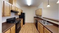 This single-floor unit offers a practical and functional layout throughout. The galley-style kitchen is well-equipped, featuring black appliances including a refrigerator, electric range, and dishwasher. Warm-toned maple cabinetry lines both walls, complemented by dark laminate countertops and a stainless steel sink. Wood-look flooring runs through the kitchen and entry area, adding a clean, durable surface underfoot. A dedicated entry foyer provides a welcoming transition into the unit, with a closet nearby for additional storage.

The living area is generously proportioned, finished with neutral carpet and recessed lighting. A sliding glass door opens to an outdoor space, allowing natural light to flow in. The layout connects smoothly to the rest of the unit via a hallway leading to the bedrooms.

The bedrooms are carpeted and finished in soft neutral tones, each featuring windows with blinds for natural light and privacy. At least one bedroom includes a walk-in closet and direct access to a bathroom. Two bathrooms serve the unit: one features a single-sink vanity with wood cabinetry and a walk-in shower, while the other includes a full tub-shower combination, both finished with tile flooring and warm neutral walls.
