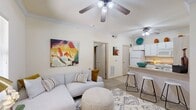 Located at 2004 S Mustang Rd in Oklahoma City, Oklahoma, this 1-bedroom, 1-bathroom residence offers a thoughtfully designed single-floor layout that maximizes functionality and comfort. The open-concept living area greets you with warm neutral tones, plush carpeting, crown molding, and a ceiling fan overhead. Natural light filters in through slatted blinds, creating a bright and welcoming atmosphere. The living room flows seamlessly into the kitchen, which features white cabinetry, a breakfast bar with counter seating, and standard appliances — ideal for casual dining and entertaining. A private bedroom provides a comfortable retreat, complete with its own ceiling fan, a window with outdoor views, and a dedicated closet for ample storage. The bathroom is clean and functional, offering a vanity with white cabinetry, tile flooring, and a well-lit mirror. Additional conveniences include an in-unit laundry area, making day-to-day living practical. Throughout the space, consistent neutral wall tones and carpeted floors lend a cohesive, move-in-ready feel. The compact yet efficient layout makes excellent use of every square foot, delivering a comfortable living experience in a well-connected Oklahoma City location.