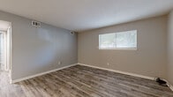 Located at 1201 S Paige St in Wichita, Kansas, this 2-bedroom, 1-bathroom single-story home offers a practical and well-appointed layout. The living room features durable wood-look laminate flooring in a neutral gray-toned finish, bright walls, and a window fitted with blinds that allows natural light to fill the space. The kitchen is efficiently designed with gray cabinetry, laminate countertops, a stainless steel sink, and stainless steel appliances including a refrigerator and range, all set on light wood-look flooring. Both bedrooms are carpeted for comfort, with soft neutral tones and windows with blinds providing natural light. The primary bedroom is a comfortable size and includes a ceiling fan with light fixture, as does the second bedroom. The full bathroom features a vanity with a granite-style countertop, gray cabinetry, overhead storage, a mirror, and a tiled tub-shower combination with wood-look flooring. The home also includes a hallway, a dedicated closet for storage, and consistent neutral gray wall tones throughout, creating a clean and cohesive aesthetic across the entire residence.