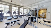 Located at 100 Underwood Dr in Summerville, South Carolina, this fitness center offers a well-appointed, single-floor exercise facility designed to support a comprehensive workout experience. The space is bathed in natural light, courtesy of expansive floor-to-ceiling windows that line the walls and provide views of the surrounding greenery, creating an open and energizing atmosphere. Ceiling fans complement the recessed lighting overhead, ensuring comfortable air circulation throughout. The cardio area is outfitted with a variety of machines, including treadmills, ellipticals, a stationary bike, and a rowing machine, catering to diverse fitness preferences. The strength training section features a multi-function cable machine, adjustable weight benches, and free weight equipment, offering users a thorough resistance training setup. Full-length mirrors extend along one wall, enhancing the sense of space while allowing users to monitor their form. The light-toned flooring and neutral color palette contribute to a clean, modern aesthetic. The layout is thoughtfully organized to provide ample space between equipment, supporting safe and efficient use of the facility. Overall, this fitness center presents a bright, functional, and well-equipped environment suited for a wide range of fitness routines.