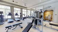 Located at 100 Underwood Dr in Summerville, South Carolina, this fitness center offers a well-appointed, single-floor exercise facility designed to support a comprehensive workout experience. The space is bathed in natural light, courtesy of expansive floor-to-ceiling windows that line the walls and provide views of the surrounding greenery, creating an open and energizing atmosphere. Ceiling fans complement the recessed lighting overhead, ensuring comfortable air circulation throughout. The cardio area is outfitted with a variety of machines, including treadmills, ellipticals, a stationary bike, and a rowing machine, catering to diverse fitness preferences. The strength training section features a multi-function cable machine, adjustable weight benches, and free weight equipment, offering users a thorough resistance training setup. Full-length mirrors extend along one wall, enhancing the sense of space while allowing users to monitor their form. The light-toned flooring and neutral color palette contribute to a clean, modern aesthetic. The layout is thoughtfully organized to provide ample space between equipment, supporting safe and efficient use of the facility. Overall, this fitness center presents a bright, functional, and well-equipped environment suited for a wide range of fitness routines.