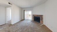 Located at 5020 Glenwood St in Mission, Kansas, this single-level unit offers three bedrooms and two bathrooms within a efficiently designed floor plan. The living room serves as the heart of the home, highlighted by a classic full-brick fireplace with a raised hearth and sliding glass doors that open onto a private balcony, bringing in natural light and outdoor views. Plush carpeting extends throughout the living room and all three bedrooms, adding warmth underfoot. The textured ceilings are consistent throughout the living and sleeping areas. The galley-style kitchen features dark cabinetry contrasted by light countertops, tile flooring, and white appliances including a range and refrigerator, with ample cabinet storage on both sides. The bedrooms are well-proportioned, with the primary bedroom offering generous space, and the secondary bedrooms each featuring windows with blinds and closet access. The two bathrooms include tile flooring; one features a full tub-shower combo with built-in wall niches, and the other includes a dark-cabinet vanity with a single sink and mirror. A hallway connects the private quarters, completing the practical and straightforward layout of this Mission, KS residence.
