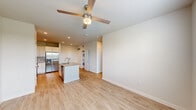 Located at 19815 Kenswick Drive in Humble, Texas, this single-story home presents a clean, contemporary design with a cohesive neutral color palette and light wood-style flooring that runs throughout the entire space.

The open-concept living and kitchen area serves as the heart of the home. The kitchen is well-appointed with crisp white shaker cabinetry, granite countertops, and a full suite of stainless steel appliances, including a French door refrigerator, electric range, and built-in microwave. A central island with an undermount sink provides additional workspace and casual dining potential. Recessed lighting and a ceiling fan with a light fixture complete the living area, creating a bright and comfortable environment.

A dedicated laundry area with a stacked washer and dryer is conveniently integrated into the layout. The bedrooms feature ceiling fans and windows with outdoor views of the surrounding greenspace, allowing for natural light. One bedroom includes a spacious walk-in closet outfitted with wire shelving systems for organized storage.

The bathroom is finished to a high standard, offering a dual-sink vanity with granite countertops, a large mirror, and a walk-in shower with striking marble-style tile surround. The overall ambiance of the home is modern, bright, and move-in ready.