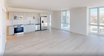 This contemporary apartment, located at 620 Foster Street in Durham, NC, offers 1210 square feet of well-designed living space. The single-floor layout includes three bedrooms, three bathrooms, and a spacious living room, creating an ideal balance of private and communal areas.

The interior is characterized by its modern aesthetic, with clean lines and a neutral color palette. Large windows dominate the living spaces and bedrooms, flooding the rooms with natural light and providing panoramic views of the surrounding cityscape. The light-colored hardwood flooring throughout adds warmth and continuity to the space.

The primary bedroom, measuring 170 square feet, offers ample space and includes an ensuite bathroom. All bathrooms feature sleek, white fixtures and finishes, with some including spacious walk-in showers with glass enclosures.

The kitchen, while not visible in the provided images, likely continues the modern theme with contemporary appliances and finishes. The open-plan living area creates a seamless flow between spaces, ideal for both relaxation and entertaining.

Additional features include ceiling fans in some rooms for improved air circulation, and sliding barn doors, adding a touch of industrial chic to the overall design. The apartment's neutral backdrop allows for easy personalization, making it a versatile canvas for various design preferences.
