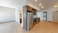 Located at 511 3rd Ave SW in Rochester, Minnesota, this single-floor unit offers a thoughtfully designed layout with contemporary finishes throughout. The open living area features light wood-tone flooring, recessed lighting, and windows with horizontal blinds that allow natural light to fill the space while offering views of the surrounding cityscape.

The kitchen is well-equipped with rich dark wood cabinetry, granite countertops, stainless steel appliances including a refrigerator, electric range, microwave, and dishwasher, as well as open display shelving for added functionality and style. The kitchen flows seamlessly into the main living area, creating an efficient and cohesive space.

The bathroom is finished with tile flooring, a dark wood vanity topped with granite countertops, a wall-mounted mirror with lighting, and a full soaking tub with a shower surround, complemented by brushed nickel fixtures throughout.

A dedicated in-unit laundry area with a stacked washer and dryer adds everyday convenience. The layout, as seen in the dollhouse view, is compact yet functional, with clearly defined zones for living, cooking, bathing, and laundry. Clean white walls and consistent flooring tie the entire space together, creating a bright, modern, and move-in-ready environment.
