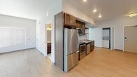 Located at 511 3rd Ave SW in Rochester, Minnesota, this single-floor unit offers a thoughtfully designed layout with contemporary finishes throughout. The open living area features light wood-tone flooring, recessed lighting, and windows with horizontal blinds that allow natural light to fill the space while offering views of the surrounding cityscape.

The kitchen is well-equipped with rich dark wood cabinetry, granite countertops, stainless steel appliances including a refrigerator, electric range, microwave, and dishwasher, as well as open display shelving for added functionality and style. The kitchen flows seamlessly into the main living area, creating an efficient and cohesive space.

The bathroom is finished with tile flooring, a dark wood vanity topped with granite countertops, a wall-mounted mirror with lighting, and a full soaking tub with a shower surround, complemented by brushed nickel fixtures throughout.

A dedicated in-unit laundry area with a stacked washer and dryer adds everyday convenience. The layout, as seen in the dollhouse view, is compact yet functional, with clearly defined zones for living, cooking, bathing, and laundry. Clean white walls and consistent flooring tie the entire space together, creating a bright, modern, and move-in-ready environment.