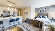 Located at 1001 South State Street in Chicago's South Loop neighborhood, this efficiently designed studio offers a thoughtful open-concept layout that maximizes every square foot. The main living area seamlessly integrates the sleeping, living, and kitchen zones, creating a cohesive and functional space. Light wood-toned flooring runs throughout, complementing the neutral gray and white color palette.

The kitchen features white cabinetry, stainless steel appliances including a refrigerator, microwave, and range, and a peninsula with bar seating — ideal for casual dining. The living area accommodates a full seating arrangement alongside the sleeping area, which is anchored by a full-size bed and accent wall.

Floor-to-ceiling windows in the sleeping area flood the space with natural light and frame sweeping views of the surrounding Chicago cityscape, offering a striking urban backdrop. A long entry corridor provides privacy and leads past two well-appointed closets — one featuring louvered bi-fold doors — as well as a dedicated laundry area with in-unit washer/dryer hookups. The full bathroom completes the layout. Clean architectural lines, modern finishes, and smart spatial planning make this studio a highly functional urban residence in the heart of Chicago.