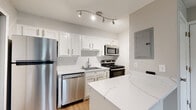 Located at 2600 Art Museum Dr in Jacksonville, Florida, this single-floor residence offers a thoughtfully updated interior with a clean, modern aesthetic. The kitchen is a standout feature, showcasing white shaker-style cabinetry, a striking marble-look quartz countertop with a matching island, a white subway tile backsplash, and a full suite of stainless steel appliances including a refrigerator, range, microwave, and dishwasher. A rail lighting fixture overhead provides focused illumination throughout the space. The open layout connects the kitchen to the main living area, which features warm wood-tone luxury vinyl plank flooring and a large window that fills the room with natural light and offers views of surrounding greenery. The bedroom is carpeted for comfort, with neutral toned walls, a ceiling fan with integrated lighting, and a window with blinds framing lush outdoor views. The bathroom is finished with wood-look flooring, a quartz-topped vanity, and a full soaking tub with shower. A dedicated in-unit stacked washer and dryer adds everyday convenience. Throughout the residence, neutral tones, crisp white trim, and consistent finishes create a cohesive and move-in-ready environment.