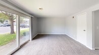 Located at 89 West Summerset Lane, this 640-square-foot, single-floor unit offers a practical and well-organized layout across one bedroom, one bathroom, and a living room. The living room is a spacious, open area featuring neutral gray walls, wall-to-wall carpeting, and a large sliding glass door that fills the room with natural light and provides views of the surrounding greenery. The kitchen, visible in the floor plan, features dark cabinetry, a countertop peninsula, and standard appliances, offering functional workspace. The bedroom spans 170 square feet with soft carpeting, neutral-toned walls, and a double window that frames outdoor tree views, creating a calm and bright atmosphere. A closet is accessible through a paneled door. The full bathroom is finished in a clean, white palette with light wood-look vinyl flooring, a tiled shower/tub combo, a white vanity with storage, and brushed nickel fixtures throughout. Ceiling light fixtures provide consistent overhead lighting across the unit. The consistent use of light gray walls and white trim throughout creates a cohesive, move-in-ready aesthetic suited for individuals or couples seeking an efficient, comfortable living space.