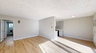 This single-floor unit offers a clean, modern aesthetic throughout, unified by warm light wood flooring and a neutral gray-and-white color palette. The open living area is bright and welcoming, with natural light streaming in through a large sliding glass door that leads to an outdoor patio, creating a seamless connection to the exterior. The textured ceiling adds a classic architectural touch to the living and bedroom spaces.

The kitchen is efficiently designed with gray shaker-style cabinetry, light countertops, a stainless steel refrigerator, a gas range, and a dishwasher. Its semi-open layout connects it conveniently to the main living area, making it practical for everyday use.

The bedrooms are generously sized, each featuring wide windows that invite natural light and views of the surrounding greenery. Mirrored sliding closet doors enhance the sense of space while providing ample built-in storage with shelving.

The bathroom is thoughtfully appointed with gray vanity cabinetry, a light countertop, and a window that brings in natural light. Consistent light wood flooring runs throughout, tying the entire space together cohesively. Overall, the unit presents a fresh, move-in-ready environment with a bright and airy ambiance.