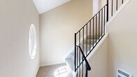 This well-appointed three-floor home in Novi, Michigan offers 2 bedrooms and 2.5 bathrooms thoughtfully distributed across its levels. The main living floor showcases an open-concept kitchen and living room, where vaulted ceilings and a bay window with natural light create an airy, welcoming atmosphere. The kitchen is outfitted with crisp white shaker cabinets, white quartz countertops, stainless steel appliances including a range and dishwasher, and a matte black faucet—combining style and functionality. The living area benefits from soaring angled ceilings and a bright bay window nook, adding architectural character throughout.

The upper floor hosts both bedrooms, including a spacious primary bedroom with dual windows and plush carpeting, accompanied by a large walk-in closet with built-in shelving and its own window. The second bedroom is well-sized and bright, suitable for various uses. The bathrooms are clean and modern, featuring white vanities with light wood-toned tile flooring; one full bath includes a tub-shower combination. A half bath provides added convenience for guests. The staircase features elegant black metal railings and is accented by a distinctive oval window that brings in natural light, enhancing the home's overall charm.