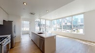Located at 1133 S Hope St in the heart of Downtown Los Angeles, this modern single-floor unit showcases a clean, contemporary design throughout. The open-concept living and kitchen area is a standout feature, anchored by a large center island with a quartz countertop, stainless steel appliances, a subway tile backsplash, and taupe cabinetry. Recessed lighting and light wood-style flooring complement the bright, airy atmosphere. Expansive floor-to-ceiling windows and corner glass walls flood the living area with natural light while framing impressive panoramic views of the Los Angeles skyline. The bedrooms are well-proportioned, each featuring large windows that continue the theme of natural light and urban views, along with ample closet space. Two bathrooms are finished with large-format tile flooring, modern vanities with white countertops, and clean chrome fixtures; one includes a soaking tub with a glass sliding enclosure. The overall design palette — crisp white walls, neutral tones, and modern finishes — creates a cohesive and sophisticated urban living environment. This unit offers an ideal blend of contemporary style and prime Downtown Los Angeles location.