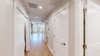 Located at 111 W Lamme St, Unit 409 in Bozeman, Montana, this one-bedroom, one-bathroom unit offers a thoughtfully designed layout across a single floor. Light wood-tone flooring flows consistently throughout, complemented by neutral warm-gray walls and clean white trim, creating a cohesive and modern aesthetic.

The combined kitchen and living area serves as the heart of the unit. The kitchen is well-appointed with dark taupe cabinetry, white subway tile backsplash, light quartz countertops, and a full suite of stainless steel appliances including a refrigerator, electric range, microwave, and dishwasher. Tall windows in the kitchen and living area flood the space with natural light and offer views of the surrounding streetscape and mature trees.

A hallway lined with recessed lighting connects the living area to the private spaces, featuring a stylish sliding barn door—a standout architectural detail. The bedroom is a calm, light-filled retreat with recessed lighting and direct access to a dedicated closet with built-in racking. The bathroom is cleanly finished with a sliding glass shower enclosure, wood-toned vanity, and consistent flooring. Recessed lighting throughout the unit ensures a bright and welcoming atmosphere in every room.