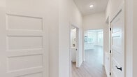 Located in Cornelius, NC, this well-designed 2-bedroom, 2-bathroom single-floor residence offers a clean, modern aesthetic throughout. The open-concept living and kitchen area is a standout, featuring light wood-look flooring, a large white quartz island with pendant lighting, white cabinetry, stainless steel appliances, and a classic subway tile backsplash. The living room is bright and airy, with a bank of large windows and a glass-paned door that floods the space with natural light, complemented by a ceiling fan overhead.

Both bedrooms are carpeted for comfort, with generously sized windows offering outdoor views, and each is accompanied by a walk-in closet with wire shelving systems. The primary bedroom connects to a well-appointed en-suite bathroom featuring a dual-sink white vanity with quartz countertops, matte black fixtures, a large mirror, and a glass-enclosed walk-in shower with tile surround. The second bathroom mirrors the same contemporary finishes. A hallway connects the rooms seamlessly, maintaining a cohesive and functional flow. The consistent use of white walls, matte black hardware, and light wood flooring throughout creates a fresh, modern, and inviting atmosphere.