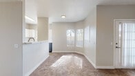 This single-floor residence offers a clean, functional layout designed for comfortable everyday living. The open-concept living and dining area is finished with plush wall-to-wall carpeting and neutral beige walls, allowing natural light to filter in through multiple windows. A peninsula counter connects the living space to the kitchen, which stands out with two-tone cabinetry — white upper cabinets paired with charcoal lower cabinets — complemented by white subway tile backsplash, light wood-look flooring, and stainless steel appliances including a range and over-the-range microwave.

The residence includes multiple bedrooms, each carpeted and finished with the same warm neutral palette. Bedrooms feature either sliding-door closets with built-in shelving or walk-in closets, providing ample storage. One bedroom is equipped with a ceiling fan and direct access to an exterior door. Natural light reaches each room through well-placed windows.

Two bathrooms serve the home. One features a wide vanity with white countertops, generous cabinet storage, and a large mirror with overhead lighting. The second bathroom includes a shower-tub combination with brushed nickel fixtures and wood-look tile flooring. The overall ambiance throughout the home is bright, neutral, and move-in ready.