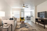This single-floor residence offers a thoughtfully designed layout that balances comfort and functionality. The open-concept living area is bright and welcoming, featuring light-toned wood-style flooring, soft neutral walls, and a ceiling fan overhead. A generously sized living room provides ample space for relaxing and entertaining, flowing seamlessly into a dedicated dining area brightened by a large window dressed with floor-to-ceiling curtains and blinds.

The kitchen is well-equipped with dark espresso cabinetry, white quartz countertops, stainless steel appliances, and a stylish herringbone tile backsplash — a standout design element that adds character to the space. Wood-style flooring continues throughout, creating a cohesive look.

The residence includes two bedrooms, each finished with plush carpeting, ceiling fans, and natural light from windows with blinds. The primary bedroom is a calm retreat with ample space for a full furniture arrangement. Both bathrooms feature dark vanity cabinetry with white countertops, a tub-shower combination with tiled surrounds, and wood-style flooring, offering a clean and modern aesthetic.

Overall, the space presents a contemporary and cohesive design with a neutral color palette accented by navy blue tones, making it a comfortable and visually appealing residence.