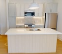 This contemporary 1-bedroom apartment offers 670 square feet of efficiently designed living space. The heart of the home is a modern, open-concept kitchen featuring crisp white cabinetry, stainless steel appliances, and a convenient island with seating. The kitchen flows seamlessly into the living area, which boasts light wood flooring and large windows that flood the space with natural light.

The bedroom, measuring 130 square feet, is carpeted for comfort and includes a window for brightness. The bathroom is well-appointed with a large vanity, undermount sink, and a glass-enclosed shower. Storage is ample throughout, with a closet visible in the bathroom area.

The apartment's design emphasizes clean lines and a neutral color palette, creating a fresh and modern ambiance. Recessed lighting and a pendant light in the kitchen area add to the contemporary feel. The layout appears to include a small hallway, connecting the various spaces efficiently.

A standout feature is the urban view from the windows, suggesting this could be a unit in a multi-story building. The overall design prioritizes functionality and style, making excellent use of the available square footage to create a comfortable and attractive living space.