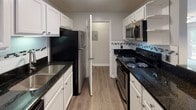 Located at 2995 Poplar Tent Rd in Concord, NC, this single-floor residence offers a well-designed layout with a thoughtful blend of functionality and comfort throughout. The kitchen is a standout feature, showcasing white shaker cabinetry, dark granite countertops, stainless steel appliances including a refrigerator, range, and microwave, as well as a decorative tile backsplash and durable wood-look flooring. A pass-through counter with pendant lighting connects the kitchen to the open living and dining area, which is finished with plush carpeting and a ceiling fan. Sliding glass doors lead from the living area to a private balcony, offering pleasant outdoor views. The bedrooms are generously sized, each featuring soft carpeting, ceiling fans with light fixtures, and windows that bring in natural light. The bathrooms are clean and functional, featuring white tub-shower combinations, granite-topped vanities with white cabinetry, and wood-look flooring. Additional details throughout the residence include neutral gray walls, white trim, and a textured ceiling finish, all contributing to a bright and cohesive aesthetic that is both practical and inviting.
