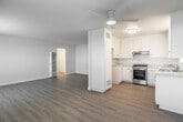 Located on Bell Circle in Huntington Beach, California, this single-story, one-bedroom, one-bathroom home offers a clean and functional layout designed for comfortable everyday living. The open-plan kitchen and living area serves as the heart of the home, featuring light wood-style flooring, neutral wall tones, and a ceiling fan that enhances airflow throughout the space. The kitchen is thoughtfully appointed with white cabinetry, light stone countertops, a stainless steel gas range with an overhead vent hood, and a double-basin sink — all arranged in a U-shaped configuration that maximizes counter and storage space. The living area flows naturally from the kitchen, with multiple windows fitted with vertical blinds allowing for adjustable natural light. The bedroom is a comfortable retreat carpeted in warm neutral tones, equipped with a ceiling fan, a sliding glass door that invites natural light and outdoor access, and a sliding-door closet providing ample storage. The bathroom is well-sized, featuring a long vanity with a light stone countertop, white cabinetry, a large mirror, pendant lighting, and light wood-style flooring, with a separate tiled shower area. A connecting hallway ties the layout together efficiently, completing this well-maintained and move-in-ready Huntington Beach home.