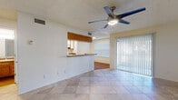 This single-story home offers a functional and well-appointed layout designed for comfortable everyday living. The main living area is bright and open, finished with large neutral-toned tile flooring and a ceiling fan with integrated lighting. A sliding glass door with vertical blinds invites natural light and provides access to the outdoors. The living space connects seamlessly to a pass-through kitchen bar, making the area feel cohesive and spacious.

The galley-style kitchen is efficiently designed with white cabinetry, granite-look countertops, hardwood flooring, a full suite of white appliances including an electric range and refrigerator, and a built-in skylight panel for additional brightness. A dedicated pantry or storage closet is conveniently located just off the kitchen.

The bedrooms are carpeted for warmth and comfort, each featuring a ceiling fan and ample natural light from well-positioned windows with blinds. One bedroom includes tile flooring and direct access to the entry door. The bathroom is cleanly appointed with full tiled walls surrounding a soaking tub and shower combination, complemented by hardwood-style flooring. Throughout the home, textured ceilings and neutral wall tones create a clean, move-in-ready aesthetic.
