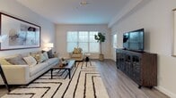 This single-floor residence on Dartmouth Street in Dartmouth, MA, offers a thoughtfully designed layout that balances functionality with contemporary style. The open-concept living area is generously proportioned, featuring light gray wood-look flooring, neutral walls, and multiple windows fitted with horizontal blinds that allow abundant natural light to filter through. The space comfortably accommodates both a seating area and additional furnishings, creating a versatile and inviting environment.

The kitchen is a standout feature, showcasing white shaker-style cabinetry, a subway tile backsplash, stainless steel appliances including a refrigerator, range, microwave, and dishwasher, along with open shelving for additional storage. A central island with a white countertop and bar seating makes it ideal for casual dining and entertaining. Pendant lighting above the island adds a refined touch.

The bedrooms are carpeted and well-lit by large windows that frame outdoor views, lending each room a calm, restful atmosphere. Both rooms offer comfortable proportions with ample wall space.

The bathroom features a white vanity with storage cabinetry, a tub and shower combination, and light-toned tile flooring, maintaining the clean, cohesive aesthetic found throughout the residence.