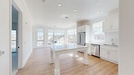 Located at 1 First Street in Oakmont, PA, this 1-bedroom, 1-bathroom residence offers a thoughtfully designed single-floor layout with a bright, open-concept living space. The combined kitchen and living area serves as the heart of the home, featuring light hardwood flooring, crown molding, and recessed lighting throughout. Large multi-pane windows on multiple walls flood the space with natural light and provide elevated views of the surrounding neighborhood.

The kitchen is well-appointed with white shaker-style cabinetry, a white quartz island, subway tile backsplash, and a full suite of stainless steel appliances including a refrigerator, range, microwave, and dishwasher. The open layout allows the kitchen to flow seamlessly into the living area.

The bedroom is carpeted for comfort, features clean white walls with ample outlets, and includes a sliding glass door that opens to a private balcony with neighborhood views—a standout feature of the space.

The full bathroom is finished with large-format tile flooring, a white vanity with a mirror and lighted fixture, a toilet, and a glass-enclosed walk-in shower. The overall aesthetic throughout is clean, modern, and move-in ready.