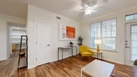 This single-story residence offers a cohesive and functional layout with hardwood-style flooring running throughout every room, creating a warm and unified aesthetic. The living area is bright and welcoming, benefiting from natural light through blinds-fitted windows that provide outdoor views. A ceiling fan with integrated lighting anchors the space, while clean white walls and neutral tones create a versatile backdrop. A dedicated dining nook adjacent to the living space accommodates a four-seat table and features wall art, adding a touch of character to the area.

The kitchen is well-equipped with light wood cabinetry, granite-style countertops, and white appliances including a refrigerator, range, dishwasher, and microwave. Ample cabinet storage and generous counter space make it highly functional.

The unit includes two bedrooms, each finished with the same hardwood-style flooring and neutral walls. The primary bedroom features a walk-in closet outfitted with multi-tier wire shelving, maximizing storage capacity, while a secondary bedroom includes a standard closet. The bathroom is efficiently arranged with a granite-topped vanity, wood cabinetry, and a tub-shower combination.