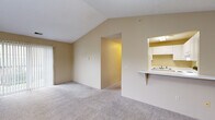 Located at 4130 W Michigan Ave in Kalamazoo, Michigan, this single-floor unit offers a well-organized layout designed for comfortable everyday living. The living area is a standout feature, boasting vaulted ceilings that lend a sense of openness and airiness to the space. Plush wall-to-wall carpeting runs throughout the living and bedroom areas, adding warmth underfoot. Large windows and a sliding glass door flood the living room with natural light while providing views of the surrounding outdoors. A chandelier adds a subtle decorative touch overhead.

The kitchen is efficiently designed with white cabinetry, ample counter space, and a full suite of appliances including an electric range and a full-size refrigerator. A pass-through counter with a breakfast bar connects the kitchen to the living area, making it ideal for casual dining or entertaining. Light tile flooring runs through the kitchen for easy maintenance.

The bedrooms are generously proportioned, each featuring soft carpeting, natural light from windows, and closet storage. One bedroom includes a sliding glass door, extending the connection to the outdoors. The full bathroom is clean and functional, featuring a wide vanity with white cabinetry, a large mirror with lighted surround, a soaking tub, and tile flooring throughout.