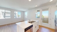 Located at 2676 New Brighton Ln in Stockton, CA, this single-story home presents a clean, contemporary aesthetic defined by bright white walls, light wood-style flooring, and an abundance of natural light throughout. The open-concept layout connects the kitchen and living areas seamlessly, creating a spacious and welcoming atmosphere.

The kitchen serves as the centerpiece of the home, anchored by a white island with a double stainless steel sink and a built-in dishwasher. White cabinetry lines the walls, complemented by a full suite of stainless steel appliances including a French door refrigerator, range, and over-the-range microwave. Recessed lighting illuminates the space, while a glass-panel exterior door provides direct outdoor access and fills the kitchen with natural light.

The living area flows naturally from the kitchen, featuring the same light wood-style flooring and multiple windows that frame views of the surrounding neighborhood. Bedrooms are carpeted for comfort, offering a quieter, cozier feel, with windows that bring in additional natural light.

The bathroom maintains the home's clean design language, featuring a white vanity with under-cabinet storage, a large mirror, and a full tub-shower combination. The consistent use of neutral tones and modern finishes throughout creates a cohesive, move-in-ready living environment.