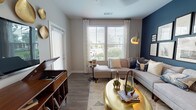 Located at 12851 Sunstone Ave in Orlando, Florida, this single-story residence offers a thoughtfully designed layout with modern finishes and a cohesive contemporary aesthetic throughout. The open-concept kitchen is a standout feature, showcasing white shaker cabinetry, a subway tile backsplash, stainless steel appliances, and a large center island with a white quartz countertop and bar seating beneath pendant lighting. Wood-look flooring connects the kitchen seamlessly to the living area.

The living room is a visually striking space anchored by a bold navy accent wall adorned with a curated gallery of framed artwork. Large windows dressed with sheer curtains and wood blinds allow generous natural light to fill the room, complementing the neutral tones and warm metallic accents throughout.

The bedrooms are carpeted and well-lit with large windows offering outdoor views. The primary bedroom includes a ceiling fan and ample space, while a hallway leads to a bathroom featuring a white vanity with quartz countertops, wood-look flooring, and a walk-in shower. Additional closet space is accessible via a dedicated hallway, enhancing overall functionality.