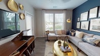 Located at 12851 Sunstone Ave in Orlando, Florida, this single-story residence offers a thoughtfully designed layout with modern finishes and a cohesive contemporary aesthetic throughout. The open-concept kitchen is a standout feature, showcasing white shaker cabinetry, a subway tile backsplash, stainless steel appliances, and a large center island with a white quartz countertop and bar seating beneath pendant lighting. Wood-look flooring connects the kitchen seamlessly to the living area.

The living room is a visually striking space anchored by a bold navy accent wall adorned with a curated gallery of framed artwork. Large windows dressed with sheer curtains and wood blinds allow generous natural light to fill the room, complementing the neutral tones and warm metallic accents throughout.

The bedrooms are carpeted and well-lit with large windows offering outdoor views. The primary bedroom includes a ceiling fan and ample space, while a hallway leads to a bathroom featuring a white vanity with quartz countertops, wood-look flooring, and a walk-in shower. Additional closet space is accessible via a dedicated hallway, enhancing overall functionality.