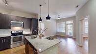 Located at 616 Oberlin Rd in Raleigh, NC, this well-appointed single-floor residence offers a contemporary open-concept layout designed for comfortable everyday living. The kitchen serves as a true centerpiece, showcasing dark espresso cabinetry, granite countertops, a large center island with an undermount sink and seating, and a full suite of stainless steel appliances including a refrigerator, range, and built-in microwave. Stylish pendant lighting and track lighting add a modern touch overhead. Warm hardwood-style flooring runs throughout the entire residence, creating a cohesive and inviting atmosphere. The open living area flows naturally from the kitchen and is brightened by large windows with views to an outdoor balcony, while a ceiling fan promotes year-round comfort. The bedrooms are generously sized with ample natural light from well-positioned windows. The bathrooms are finished with granite-topped vanities, dark cabinetry, and a glass-enclosed shower, mirroring the upscale finishes found throughout. Neutral wall tones and clean white trim provide a versatile backdrop. Wide hallways connect the rooms with ease, and the overall layout is both functional and aesthetically refined, making this Raleigh residence a polished and practical living space.