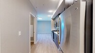 Located at 4901 Broadway in Oakland, CA, this thoughtfully designed unit offers a well-organized layout across a single floor, encompassing a living room, kitchen, bathroom, closet, and entrance. Light-toned luxury vinyl plank flooring runs throughout, lending a clean and cohesive aesthetic to the entire space.

The kitchen is a standout feature, outfitted with rich dark-wood cabinetry, open shelving, stainless steel appliances including a gas range, built-in microwave, and refrigerator, along with a white quartz countertop and a geometric hexagonal tile backsplash that adds a modern touch. An undermount stainless steel sink completes the functional workspace.

The living area is bright and open, benefiting from large picture windows that frame views of the surrounding Oakland neighborhood and allow abundant natural light to fill the room. Neutral gray walls complement the light flooring and create a calm, contemporary atmosphere.

The bathroom features light tile flooring, a clean white soaking tub with shower, and a minimalist design. The dedicated closet includes a full-width hanging rod and shelf, offering practical storage. A welcoming entrance corridor connects the kitchen and living spaces seamlessly, completing this efficiently planned urban residence.