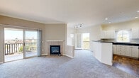 This well-appointed single-floor residence in Chula Vista, California offers three bedrooms, two bathrooms, and a thoughtfully designed layout. The open-concept living and dining area serves as the heart of the home, highlighted by a tile-surround fireplace, crown molding, and plush wall-to-wall carpeting. Sliding glass doors and a French door lead to two separate balconies, flooding the space with natural light and providing outdoor views of the surrounding neighborhood. The kitchen is outfitted with crisp white shaker cabinetry, dark granite-style countertops, hardwood-style flooring, a gas range, built-in microwave, refrigerator, and a peninsula that opens toward the living area—ideal for both cooking and entertaining. Each bedroom features soft carpeting and natural light from windows with blinds, while the generously sized primary bedroom includes a ceiling fan and ample room. The bathrooms echo the kitchen's design aesthetic with matching dark countertops and white vanities. A dedicated in-unit laundry room accommodates a full-size washer and dryer. Crown molding and consistent neutral tones throughout contribute to a cohesive and comfortable ambiance across this well-maintained Chula Vista residence.