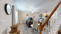 Located at 2015 Empress Drive in Murfreesboro, Tennessee, this two-story home offers a well-organized layout spread across two floors. The main level features a welcoming living area with warm neutral tones, hardwood-style flooring, crown molding, a ceiling fan, and a textured ceiling. A wooden staircase with a classic turned newel post connects the two levels. The kitchen is equipped with warm oak cabinetry, dark countertops, black appliances, and tile flooring. An adjacent dining area benefits from natural light through large windows dressed with grommet-panel curtains, creating a bright and comfortable space for meals. Three bathrooms are distributed throughout the home, each finished with tile flooring, wood-toned vanities, and tub-shower combinations. The two bedrooms are located on the upper level, both featuring vaulted ceilings and plush carpeting. The spacious primary bedroom offers generous proportions with an en-suite bathroom accessible through the hallway. The secondary bedroom is cozy and well-lit, with a window allowing natural light to fill the room. Throughout the home, neutral wall colors and consistent finishes create a cohesive and inviting ambiance suited for comfortable everyday living.