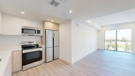 Located at 2600 S Sepulveda Blvd in Los Angeles, this modern 3-bedroom, 3-bathroom residence offers a thoughtfully designed single-level layout with clean lines and contemporary finishes throughout. Light wood-tone flooring flows through the open-plan kitchen and living area, which is anchored by a sleek kitchen featuring white upper cabinetry, warm wood lower cabinets, stainless steel appliances including a French door refrigerator, electric range, microwave, and dishwasher. Recessed lighting illuminates the space, enhancing its bright, airy character. The three bedrooms are well-proportioned, with plush carpeting, ample closet storage, and crisp white walls. The primary bedroom opens via sliding glass doors to a private patio offering panoramic views of the surrounding Los Angeles neighborhood. Each of the three bathrooms is finished with tile flooring, a tub-shower combination with glass enclosure, and wood-accented vanities. Connecting hallways are clean and bright, maintaining the home's cohesive modern aesthetic. An additional outdoor patio space provides a generous area for relaxing or entertaining under the open sky, with sweeping views of the cityscape and lush treetops — an ideal retreat in the heart of West Los Angeles.