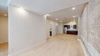 Located in New Orleans, LA, this one-bedroom, one-bathroom unit masterfully balances historic character with contemporary design. The open living area immediately draws attention with its striking exposed brick walls, which serve as a defining architectural feature throughout the space. Light hardwood flooring extends seamlessly across the unit, complementing the clean white walls and recessed lighting to create a bright, cohesive atmosphere.

The kitchen is a functional centerpiece, featuring rich dark wood cabinetry, stainless steel appliances including a French door refrigerator and range with a sleek wall-mounted hood vent, a marble-topped island with an undermount sink, and a mosaic tile backsplash. Track lighting and a pendant fixture illuminate the space efficiently.

The bathroom is finished with marble-look tile flooring and wall surround, a dark wood vanity with a white countertop, and a tiled shower, conveying a clean, upscale aesthetic. A dedicated laundry room provides added convenience with a full-size washer and dryer and built-in wire shelving. Large steel-framed windows in the bedroom area allow natural light to highlight the textured brick walls, reinforcing the unit's distinctive industrial-meets-refined character.
