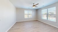 Located at 100 Fair Oaks Dr in Savannah, GA, this well-appointed single-story home offers two bedrooms, two full bathrooms, and a thoughtfully designed open floor plan. Light wood-style luxury vinyl plank flooring runs throughout the main living areas, creating a clean, cohesive aesthetic.

The kitchen serves as a central hub of the home, featuring bright white shaker cabinetry extending to the ceiling, a full suite of stainless steel appliances including a refrigerator, electric range, microwave, and dishwasher, and a light-toned countertop island that provides additional prep and seating space. Recessed lighting illuminates the area efficiently.

The bedrooms offer a comfortable retreat, with plush carpeting and ceiling fans for year-round comfort. Each bedroom benefits from windows fitted with blinds, allowing natural light and outdoor views. The generously sized primary bedroom includes direct access to a walk-in closet outfitted with wire shelving and hanging rods, as well as an en-suite bathroom featuring a tub-shower combo with white subway tile surround, wood-tone flooring, and white vanity cabinetry. The second full bathroom mirrors the same clean, contemporary finishes. A hallway with recessed lighting connects all areas of the home efficiently, completing this functional and modern layout.