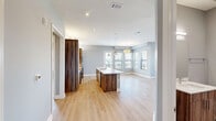 Located at 1812 Hickory St in Dallas, TX, this modern 2-bedroom, 2-bathroom home offers a thoughtfully designed single-floor layout with high-end finishes throughout. The open-concept kitchen and living area serves as the heart of the home, featuring rich wood cabinetry, a large quartz waterfall island with an undermount sink and gold-tone faucet, stainless steel appliances, and stylish pendant lighting. Light hardwood flooring flows seamlessly throughout the main living spaces, complementing the cool gray walls and crisp white trim. The living room is highlighted by an electric fireplace and a bank of windows framing impressive views of the Dallas skyline. A private balcony with modern metal railings and a wood-paneled ceiling extends the living space outdoors, offering sweeping city views. The generously sized primary bedroom includes dedicated closet space, while both bathrooms are finished with wood-toned vanities, quartz countertops, large-format tile flooring, and glass-enclosed walk-in showers accented with hexagonal tile. The second bedroom benefits from natural light through a sizable window with city views. Recessed lighting and ceiling fans are featured throughout, adding to the clean, contemporary aesthetic of this well-appointed Dallas home.