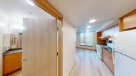 Located at 1801 E Yesler Way in Seattle's vibrant Capitol Hill neighborhood, this efficiently designed unit makes smart use of its compact footprint across a single floor. Light wood flooring runs throughout the space, creating a warm, cohesive aesthetic that ties each area together seamlessly.

The kitchen is well-appointed with warm-toned wood cabinetry extending floor to ceiling, offering generous storage. It includes an electric range with overhead ventilation, a stainless steel sink, ample counter space with gray laminate surfaces, and a full-size refrigerator — providing all the essentials for everyday cooking.

The main living area benefits from large windows fitted with vertical blinds, allowing natural light to fill the room while offering views of the surrounding Seattle cityscape and treetops. Recessed lighting supplements the natural light, keeping the space bright and welcoming.

Two bathrooms serve the unit, one of which features a wide vanity with wood cabinetry, a stone-tone countertop, dual mirrors, and accessibility grab bars — reflecting a thoughtful, functional design. A sliding wood-panel door adds a modern, space-saving touch to the interior layout.

Overall, the unit presents a clean, contemporary design with warm wood accents, practical finishes, and a well-organized layout suited for efficient urban living in Seattle.