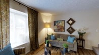 Located in Reynoldsburg, Ohio, this two-story home at 735 Marlan Ave offers a comfortable and well-appointed living environment. The interior is characterized by a warm, neutral color palette complemented by thoughtfully chosen décor throughout.

The living area is a welcoming focal point of the home, featuring hardwood-style flooring that adds warmth and character to the space. A textured ceiling adds subtle visual interest overhead, while a large window dressed with elegant, floor-length patterned drapery allows natural light to filter into the room. The space is well-suited for relaxed everyday living, with ample room for seating and furnishings.

Wall décor, including framed artwork and decorative mirrors, contributes to the curated, homey ambiance. Accent lighting from a standing floor lamp enhances the inviting atmosphere, particularly in the evenings.

Spread across two floors, the home provides a practical separation of living and private spaces, offering both functionality and comfort. The overall design aesthetic balances casual warmth with tasteful detail, making it a welcoming residence in the established Reynoldsburg community, conveniently situated with access to local amenities and the greater Columbus metropolitan area.