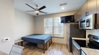 Located at 1033 East Sawmill Road in Flagstaff, AZ, this efficiently designed studio unit makes excellent use of its compact footprint across a single floor. The main living area features warm wood-look flooring, neutral walls, and a ceiling fan with integrated lighting, creating a comfortable and functional environment. A window with blinds allows natural light to brighten the sleeping area, which includes a raised bed frame with under-bed storage. A dedicated desk nook with a thermostat and multiple outlet access points provides a practical workspace.

The kitchen is well-appointed with dark wood cabinetry, granite-style countertops, white subway tile backsplash, and a full suite of stainless steel appliances including a refrigerator, electric range, and over-the-range microwave. A stainless steel sink rounds out the culinary space, offering all the essentials for daily meal preparation.

The bathroom is finished with wood-look tile flooring, dark cabinetry with storage, a granite-topped vanity, and a walk-in shower with clean white tile surround. A safety grab bar adds thoughtful functionality to the space. The unit's modern finishes and efficient layout make it a practical option in the Flagstaff area.