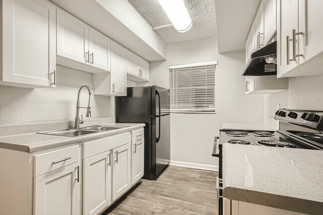 Cocina luminosa y moderna con elegantes armarios blancos, encimeras refinadas y grifería de acero inoxidable que crean un espacio culinario sofisticado. - Alderman Park Apartments