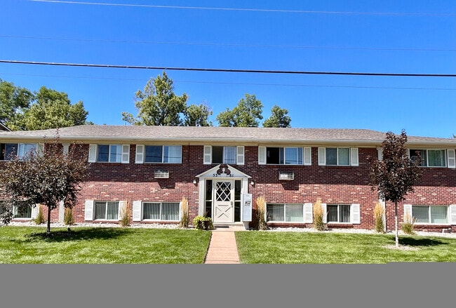 Charming brick apartment building with well-maintained lawn and mature trees under a clear blue sky. - 5351 Delaware